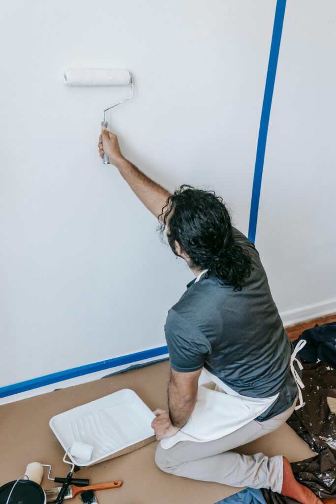 Adult man painting a wall with a roller during a home renovation project indoors.